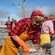 Women on a dock sorting herring while wearing aprons and rubber gloves